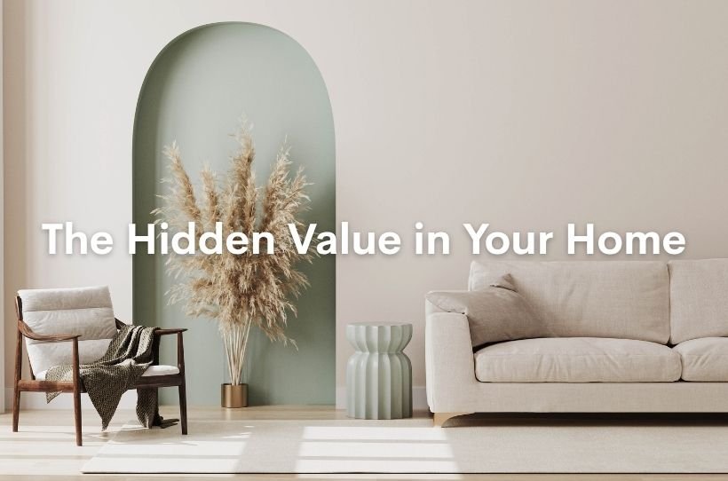 Modern living room with neutral decor, featuring a beige sofa, wooden chair, and dried pampas grass in a green alcove, with text reading 'The Hidden Value in Your Home